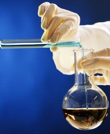 two-hands-pour-contents-of-test-tube-into-laboratory-flask-155006089-bb2d09effc1f49d3b795ebee993b98aa